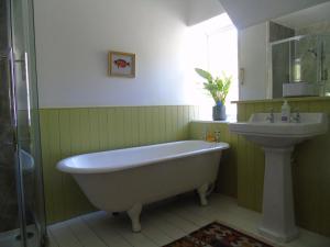 a bathroom with a white tub and a sink at Rowan Cottage, CrannachCottages in Garve