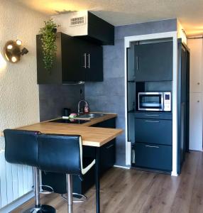 a kitchen with black cabinets and a wooden counter top at Studio lumineux neuf dans l'hyper centre avec vue in Chamonix