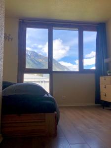 ein Schlafzimmer mit einem Bett und einem großen Fenster in der Unterkunft Studio lumineux neuf dans l'hyper centre avec vue in Chamonix-Mont-Blanc