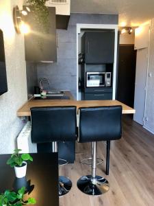 a kitchen with a counter with black chairs in it at Studio lumineux neuf dans l'hyper centre avec vue in Chamonix