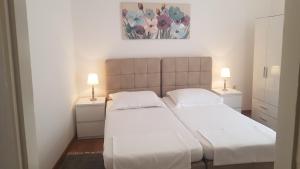 two beds in a small bedroom with two lamps at Apartments Andrea in Šibenik