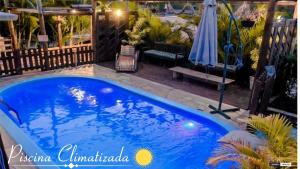 a blue swimming pool on a patio with an umbrella at Pousada Carolina in Penha