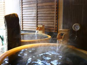 a hot tub with a water fountain in a room at Onyado Nono Kanazawa in Kanazawa