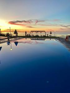 a large swimming pool with a sunset in the background at Nautica Hotel Apartments in Stavromenos