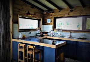 a kitchen with blue cabinets and two windows and a sink at CASA BARCA DE CHILOÉ in Castro