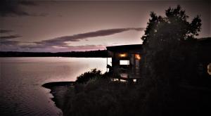 a cabin on the shore of a lake at night at CASA BARCA DE CHILOÉ in Castro +6 photos