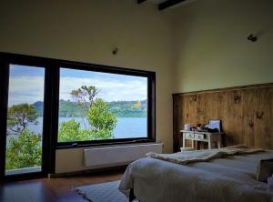 a bedroom with a large window with a view of the water at CASA BARCA DE CHILOÉ in Castro