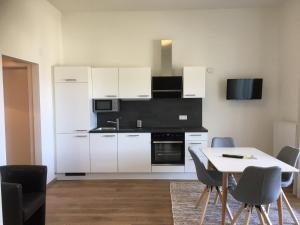 a kitchen with white cabinets and a table and chairs at Appartements Käthe in Faak am See