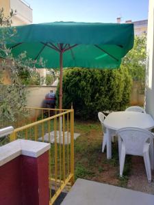 - un parasol vert sur une terrasse avec une table et des chaises dans l'établissement kamenjak, à Premantura