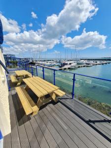 a wooden deck with a bench and boats in the water at Carlingford Marina Apartments in Carlingford