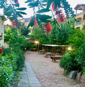 un jardín con bancos, árboles y flores en Borgo Bellavista Badesi, en Badesi