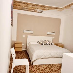 シラクーサにあるCasa vacanze Simopieroのベッドルーム(白いベッド1台、白い椅子付)
