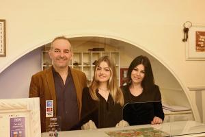 Een man en twee vrouwen staan aan een toonbank in een winkel. bij Albergo Etruria in Volterra