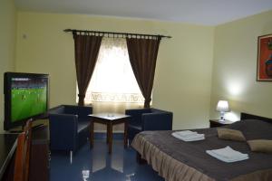 een hotelkamer met een televisie, een bed en een tafel bij Hostel Franica in Kuršumlija