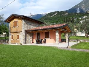 a small stone house with a patio and mountains in the background at Villa Pia in Malcesine