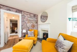 a living room with yellow furniture and a fireplace at The Riddoch Apartment by The National Trust Scotland in Edinburgh