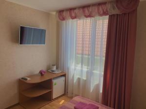a bedroom with a window with a desk and a television at Guest House Romashka in Feodosia