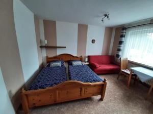 1 dormitorio con 2 camas y sofá rojo en Goode Wind, en Norden