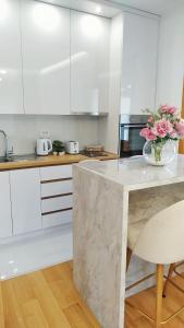 een keuken met witte kasten en een tafel met bloemen erop bij Apartman PROHOR in Zlatibor