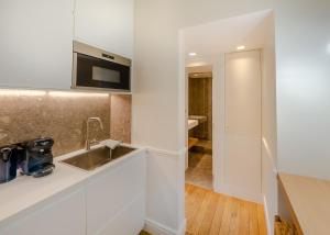 a white kitchen with a sink and a microwave at Appartement de standing 1 – tour Eiffel/Invalides in Paris