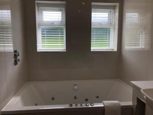 a white bath tub in a bathroom with two windows at Exeter Court Hotel in Exeter