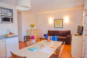 a living room with a white table and a kitchen at Résidence Goélia Aquaresort in Nérac