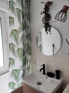 a bathroom with a sink and a green leafy shower curtain at L'escapade in La Bourboule