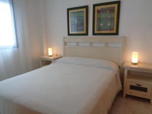 1 dormitorio con 1 cama blanca y 2 mesitas de noche en Ada Calypso Apartamento, frente al mar y castillo, Parking, Aire acondicionado, WiFi, Piscina, en Peñíscola