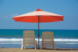 Dos sillas y una sombrilla en la playa en Balcon del Mar Beach Front Hotel, en Jacó