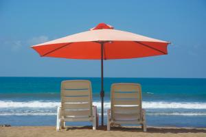 two chairs and an umbrella on the beach at Balcon del Mar Beach Front Hotel in Jacó