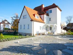 a white house with an orange roof on a cobblestone street at Villa Seenland in Böhlen