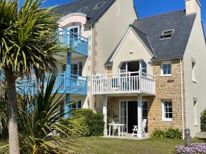 een groot huis met blauwe balkons en een tuin bij Residence Cap Marine in Le Guilvinec