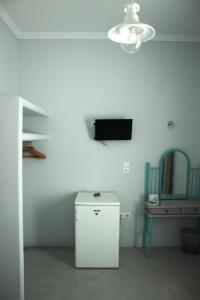 a room with a small refrigerator and a tv on the wall at Passos Rooms in Parikia