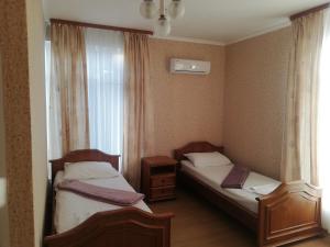 two beds in a small room with a window at Guest House Assol in Loo