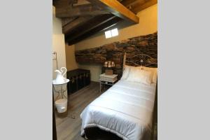 1 dormitorio con cama y pared de piedra en El Refugio del Alquimista - Casa rural - Médulas, en Puente de Domingo Flórez