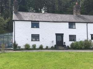 uma casa branca com um relvado verde em frente em Historic 17th century farmhouse in Wales em Gwernymynydd