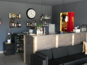 eine Bar mit einer Theke mit einer Uhr an der Wand in der Unterkunft Hôtel L'Agape in Thermes-Magnoac