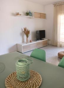 uma sala de estar com uma mesa verde e uma televisão em Apartamento Eucaliptus B - Delta del Ebro em L'Eucaliptus