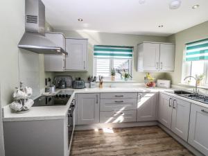 a white kitchen with white cabinets and a sink at 7 Parc Delfryn in Brynteg