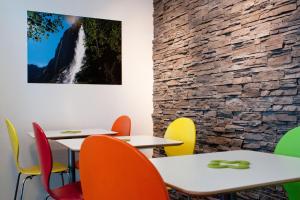a restaurant with tables and chairs with a waterfall painting on the wall at Valley Hostel in Lauterbrunnen