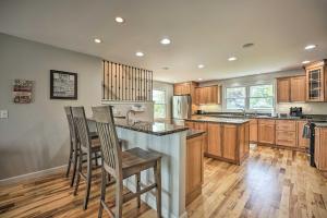 a kitchen with wooden cabinets and a island with bar stools at Pet-Friendly Grass Lake Retreat with Game Room! in Grass Lake