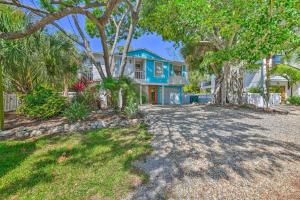 a large blue house with trees in front of it at Canalfront Anna Maria Cottage with Pool and Hot Tub! in Anna Maria