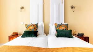 a bedroom with a bed with white sheets and green pillows at LeL Madalena GuestHouse in Lisbon