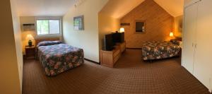 een hotelkamer met 2 bedden en een televisie bij Snowy Owl Inn in Waterville Valley