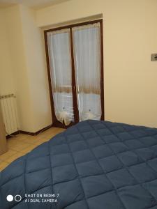 sypialnia z niebieskim łóżkiem i oknem w obiekcie Mamma Giulia w mieście Stroncone
