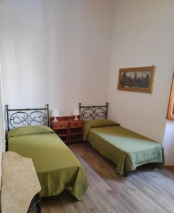 a room with two beds with green sheets and a table at Accanto al Duomo in Florence