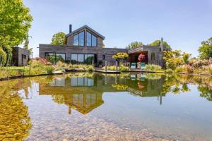 a house with a pond in front of it at Gite La Basse-Cour in Cordemais