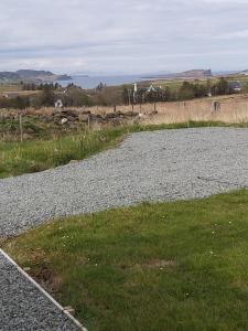 a gravel road with grass on the side of a field at Self-catering Cottage at Benview in Staffin +3 photos