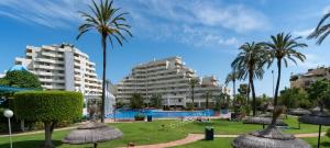 ośrodek z basenem, palmami i budynkami w obiekcie Benalbeach w mieście Benalmádena
