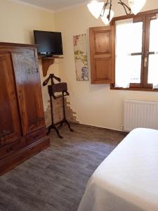 Schlafzimmer mit einem Bett, einem TV und einer Kommode in der Unterkunft Hotel La Llosona in Ribadesella